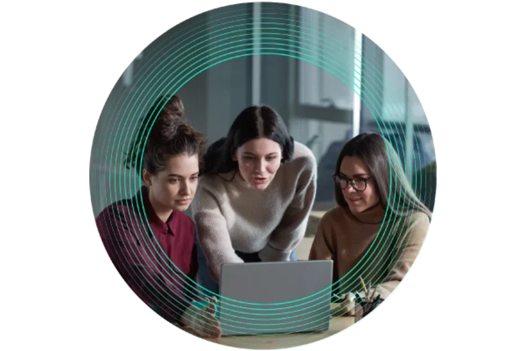 3 female colleagues sitting around a laptop, discussing work happily