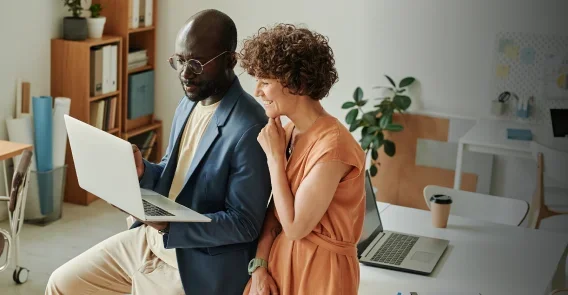 2 co-workers talking over an idea on a laptop